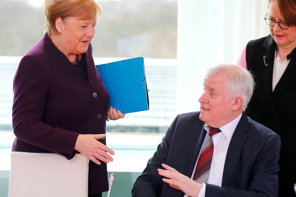 Germany’s interior minister rebuffs Chancellor Angela Merkel’s attempt to shake hands with him. Photo: Reuters