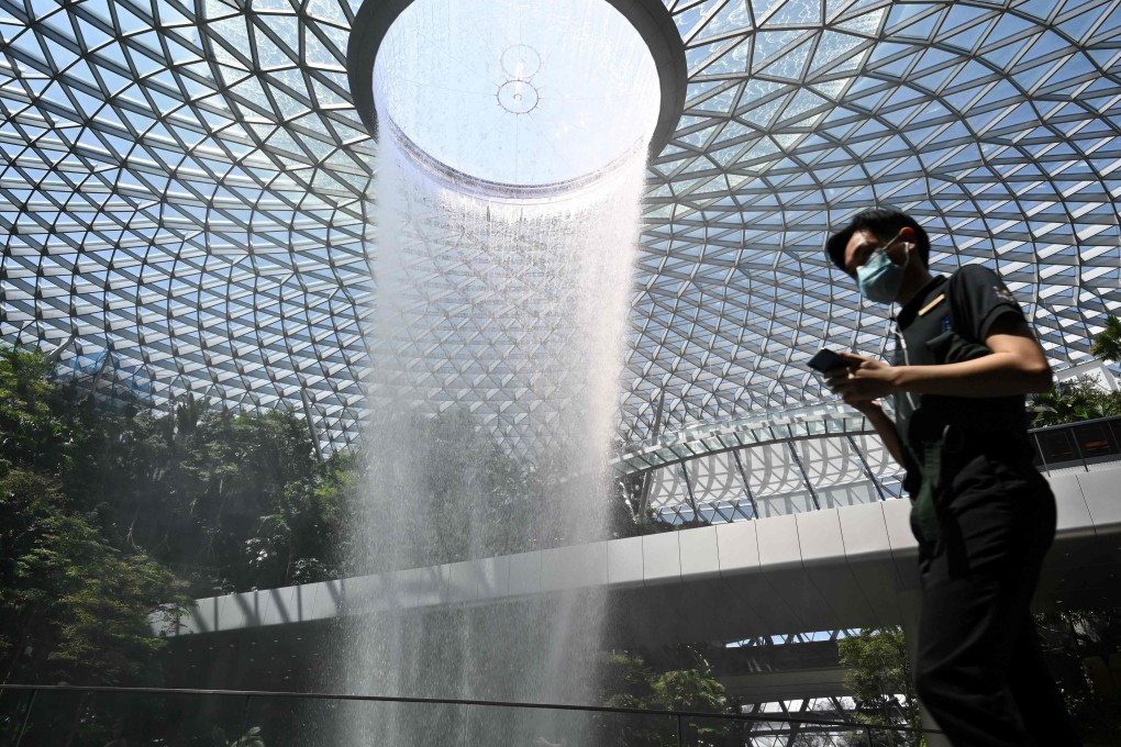 A man wearing a face mask walks past the Rain Vortex display at Jewel Changi Airport in Singapore. Photo: AFP