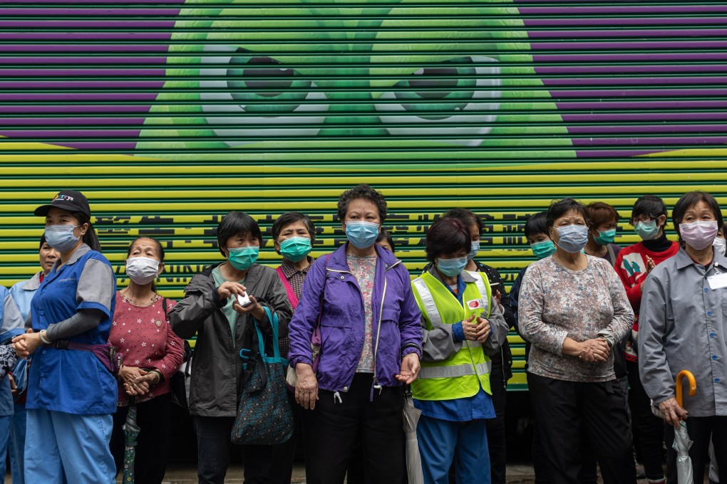 Street cleaners in Hong Kong wait in line to receive free face masks on February 14. Low-skilled workers have little savings are most vulnerable in an economic downturn. Support for business owners must come with protection for these workers. Photo: EPA-EFE
