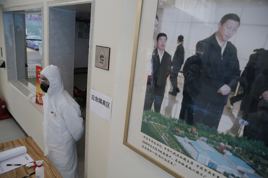 A worker wearing a protective body suit stands near a framed picture of President Xi Jinping at a dairy factory in Beijing on February 27. Photo: EPA-EFE