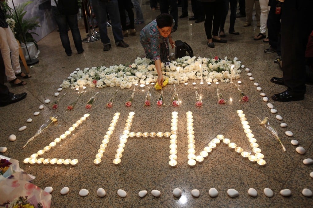 A Malaysia Airlines crew member places a flower next to candles forming MH17 after a multi-faith prayers for the victims. Photo: AP Photo