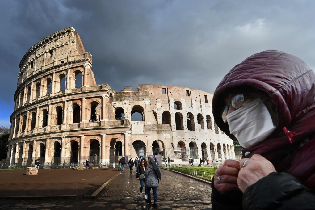 A man wearing a protective mask passes by the Coliseum in Rome. Photo: AFP