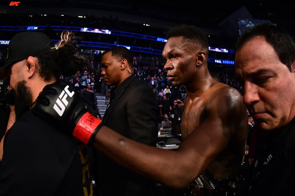 Israel Adesanya is escorted out of the Octagon after a decision win over Yoel Romero at UFC 248. Photo: AFP