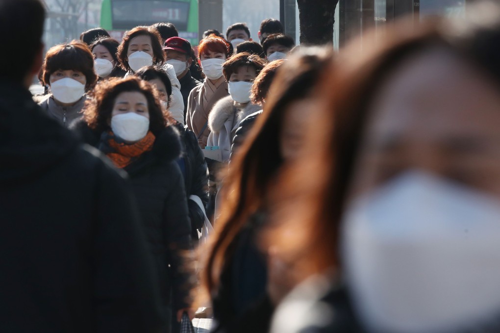 People wearing face masks wait to take public buses at a bus stop in Seoul. Photo: AFP