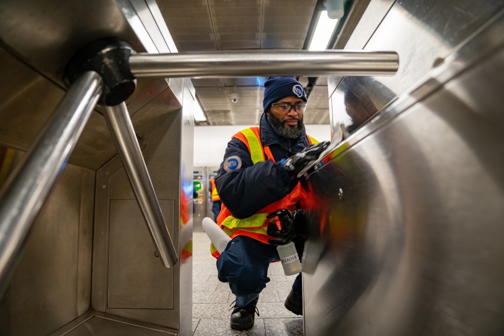 A Metropolitan Transportation Authority worker sprays disinfectant and wipes a turnstile. Photo: Bloomberg