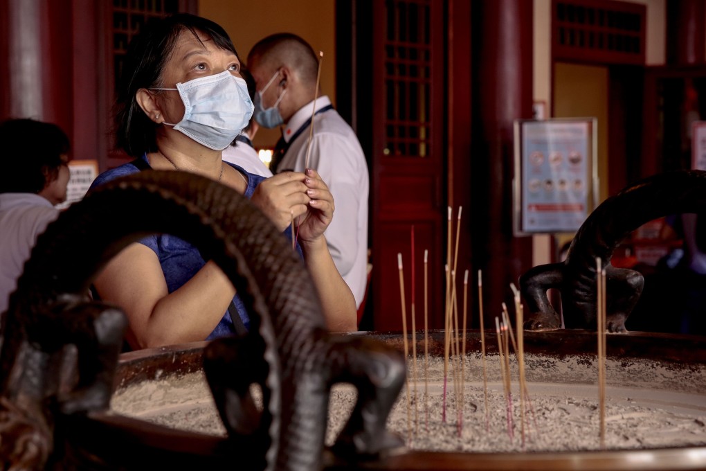 People wearing surgical masks pray at the Buddha Tooth Relic Temple in the Chinatown district of Singapore. Photo: EPA