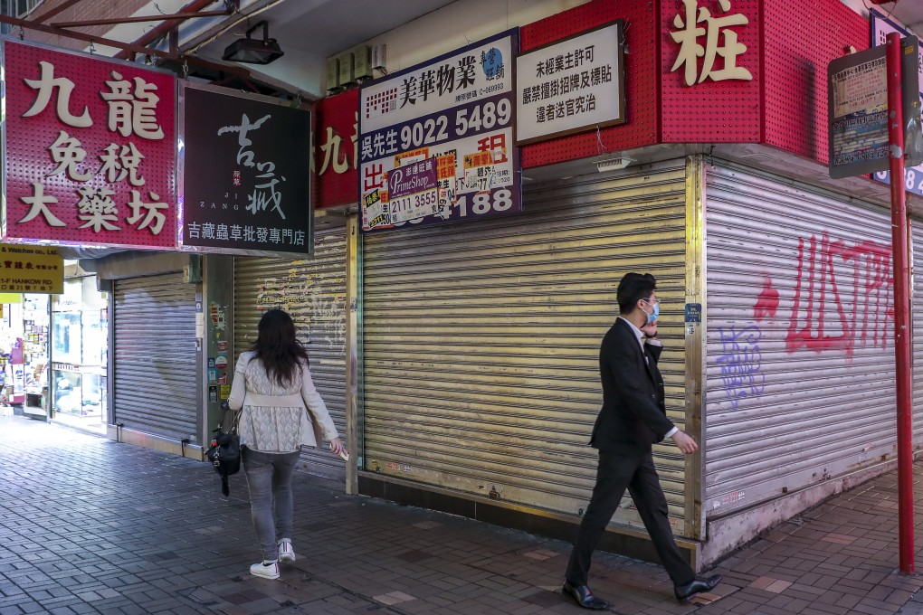 Pedestrians wearing protective face masks walk past shuttered shops as the coronavirus outbreak continues in Hong Kong. Photo: Edmond So