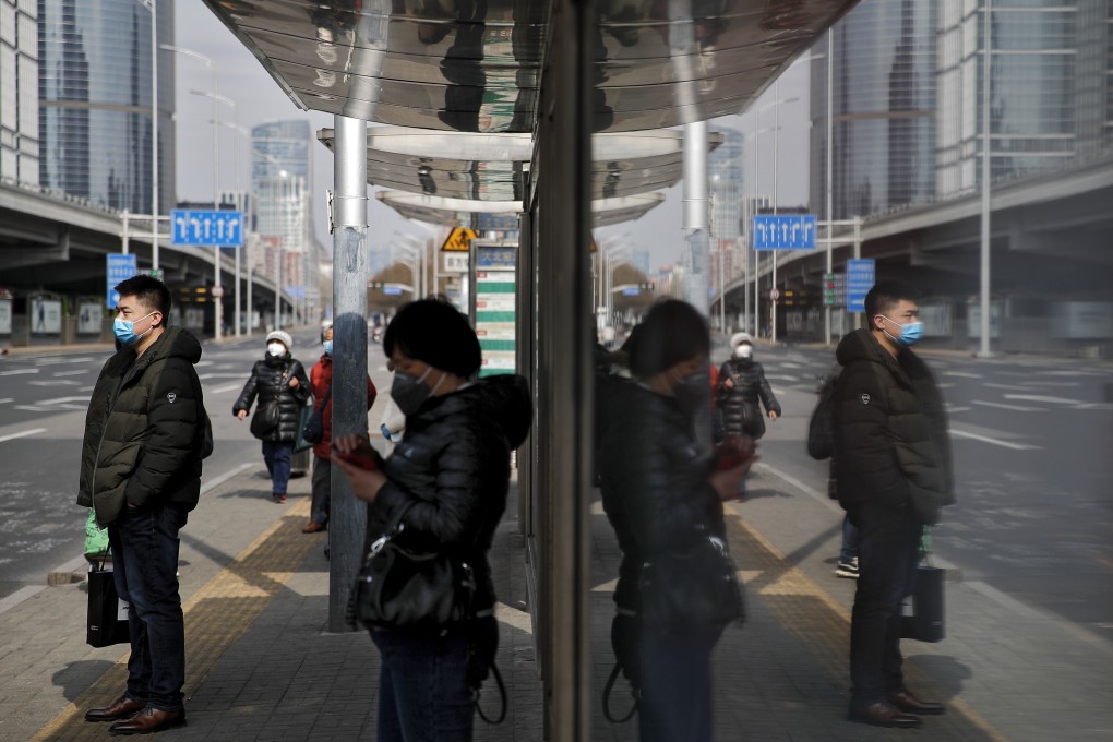 Commuters wearing protective face masks wait for buses at a stop in the Central Business District in Beijing, Monday, March 2, 2020. China's manufacturing plunged in February as antivirus controls shut down much of the world's second-largest economy. Photo: AP