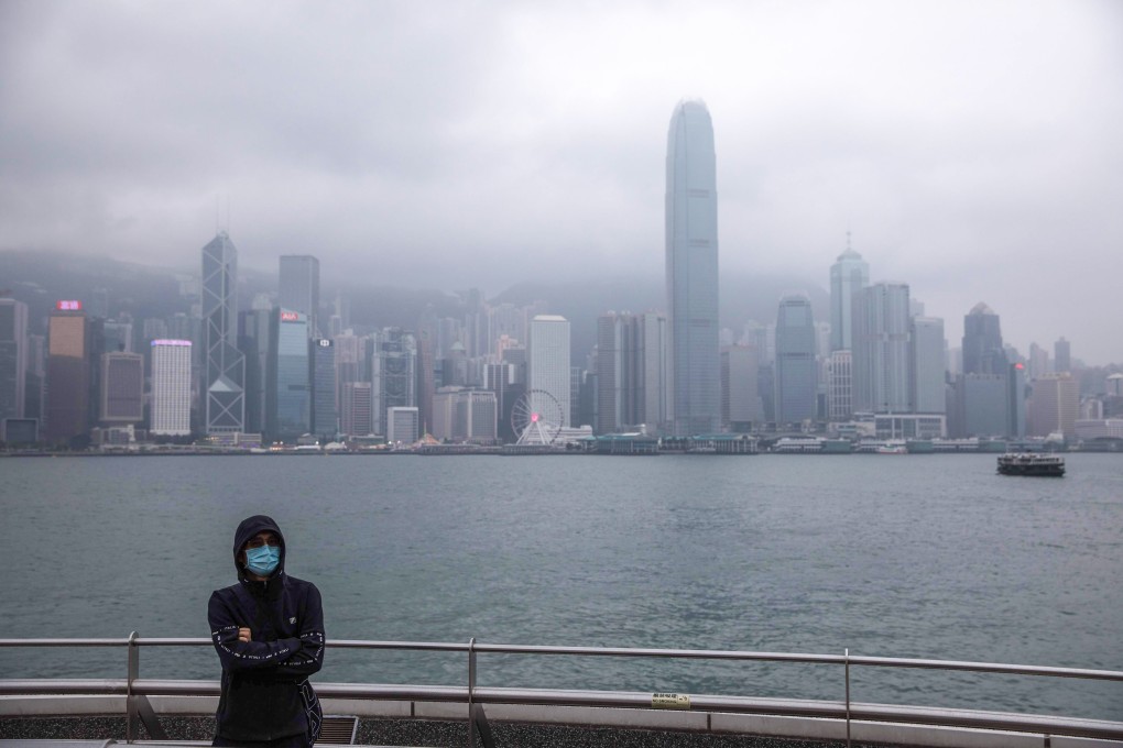 A man wearing a face mask is flanked by the Hong Kong skyline in Tsim Sha Tsui on January 25. The coronavirus epidemic has emptied streets in some of Hong Kong’s busiest areas. Photo: AFP