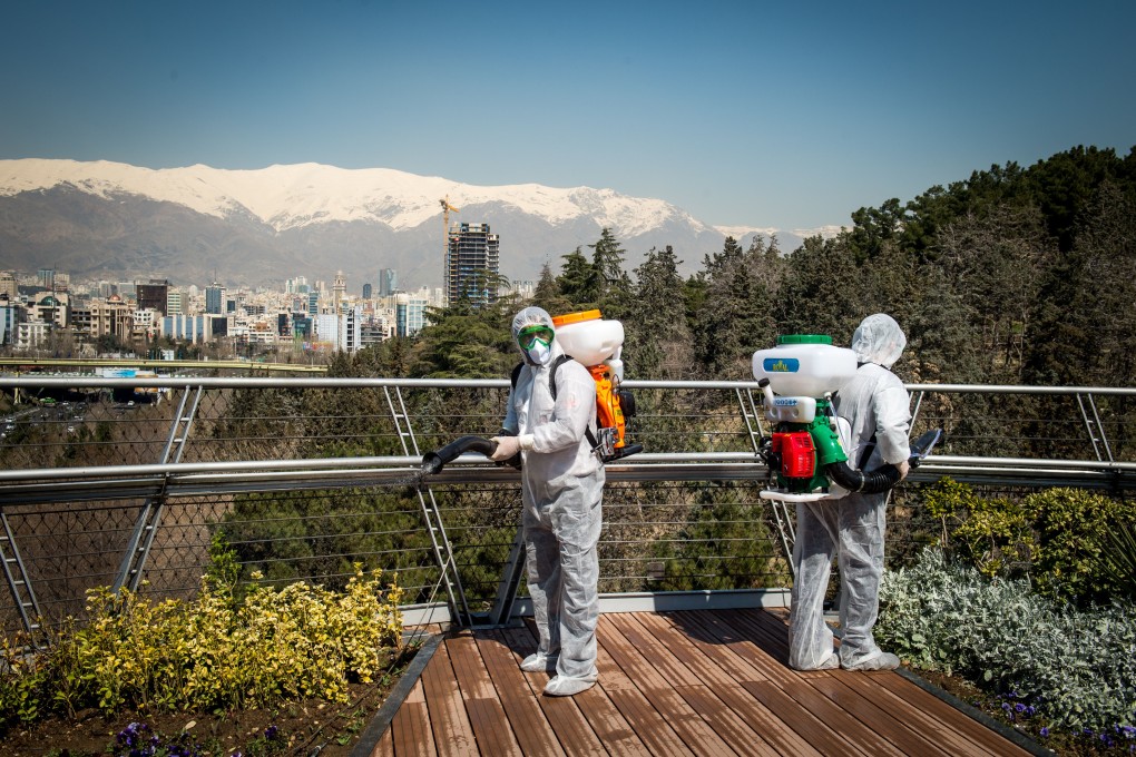 Firefighters wearing protective clothing spray disinfectant on Tabia’t bridge pedestrian overpass in Tehran, Iran. Photo: Bloomberg