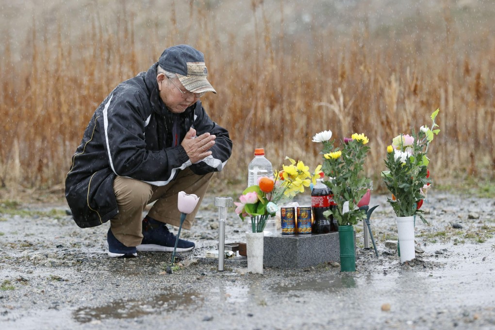 A bereaved father mourns his lost son, who went missing in the tsunami, at a memorial in Namie, Fukushima Prefecture, on Monday. Photo: Kyodo