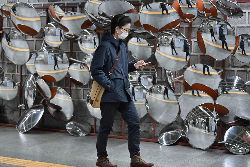A commuter wearing a mask walks past mirrors at a subway station in Seoul on March 12. Photo: AFP