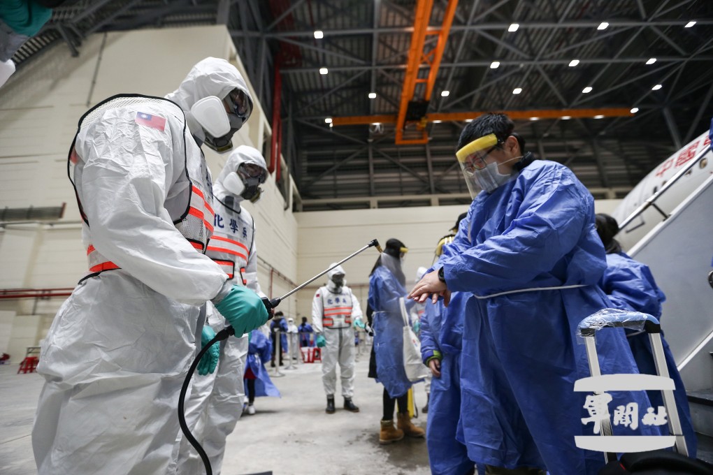 Soldiers in protective suits disinfect Taiwanese evacuees from Hubei, after their China Eastern Airlines flight landed at Taoyuan International Airport on Tuesday night. Photo: EPA-EFE / Handout from Ministry of National Defence