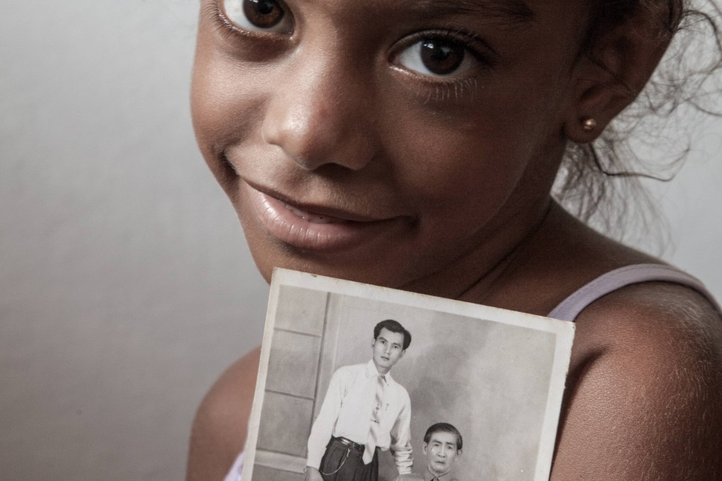 A mixed-race child in Chinatown in Havana, Cuba, holds up a photograph of her Chinese forebears. Photo: Lau Pok-chi