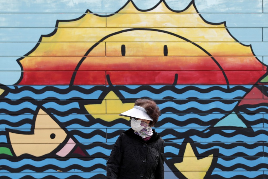 A woman wearing a face mask walks along the Han river at a park in Seoul, South Korea. Photo: AP