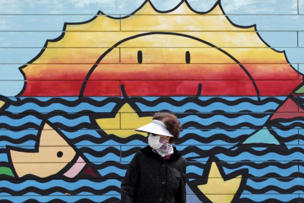 A woman wearing a face mask walks along the Han river at a park in Seoul, South Korea. Photo: AP