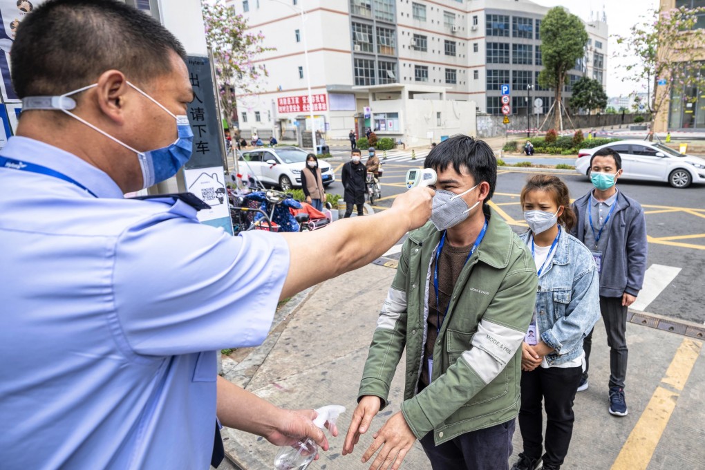 A security guard checks employees body temperature and disinfects their hands at the entrance to a factory in Shenzhen. Photo: EPA-EFE