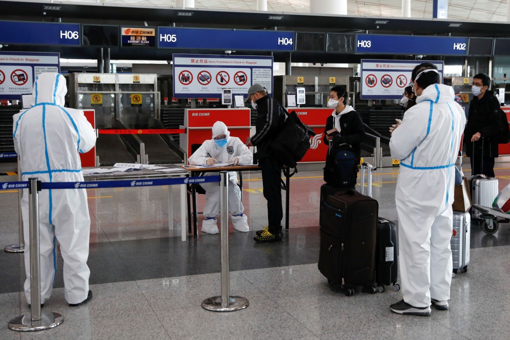 Staff in protective suits register passengers at Beijing Capital International Airport. Photo: Reuters