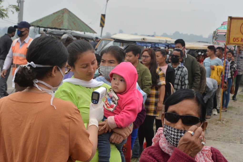 A worker checks the temperature of travellers at the India-Nepal border at Panitanki checkpoint on March 14, 2020. Photo: AFP
