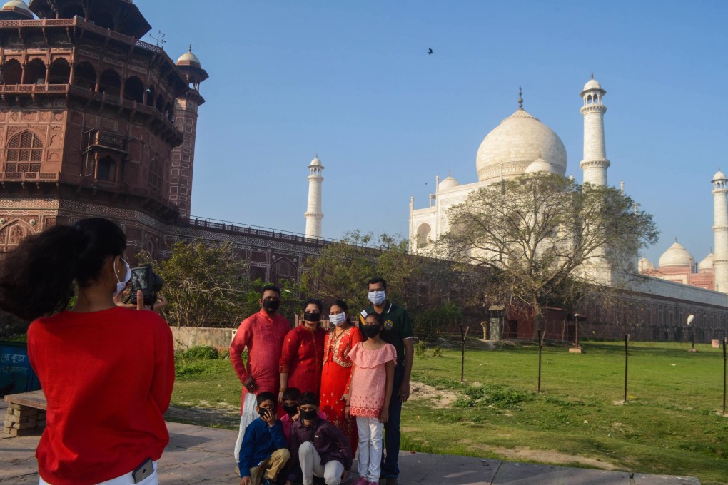 Visitors wearing face masks as a preventive measure against the Covid-19 coronavirus have their picture taken outside Taj Mahal in Agra, India, following its temporary closure. Photo: AFP