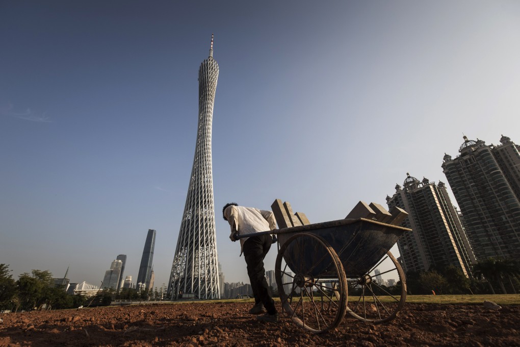 A worker pulls a cart in front of the residential and commercial buildings, including the Canton Tower, in Guangzhou, China, in November 2017. A report published by an investment bank noted that work had resumed at half the building sites among developers it covers. Photo: Bloomberg