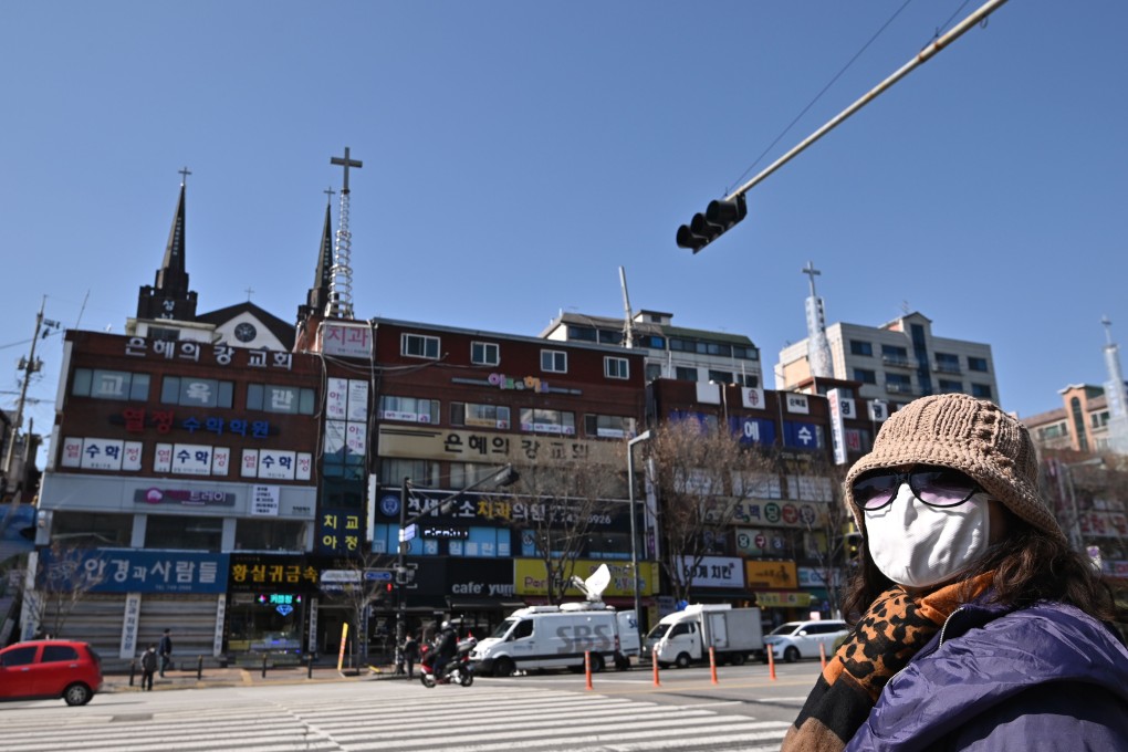 A woman wearing a face mask crosses a road in front of a building housing the Grace River Church, where 46 people were confirmed to have the Covid-19 coronavirus, in Seongnam, South Korea. Photo: AFP