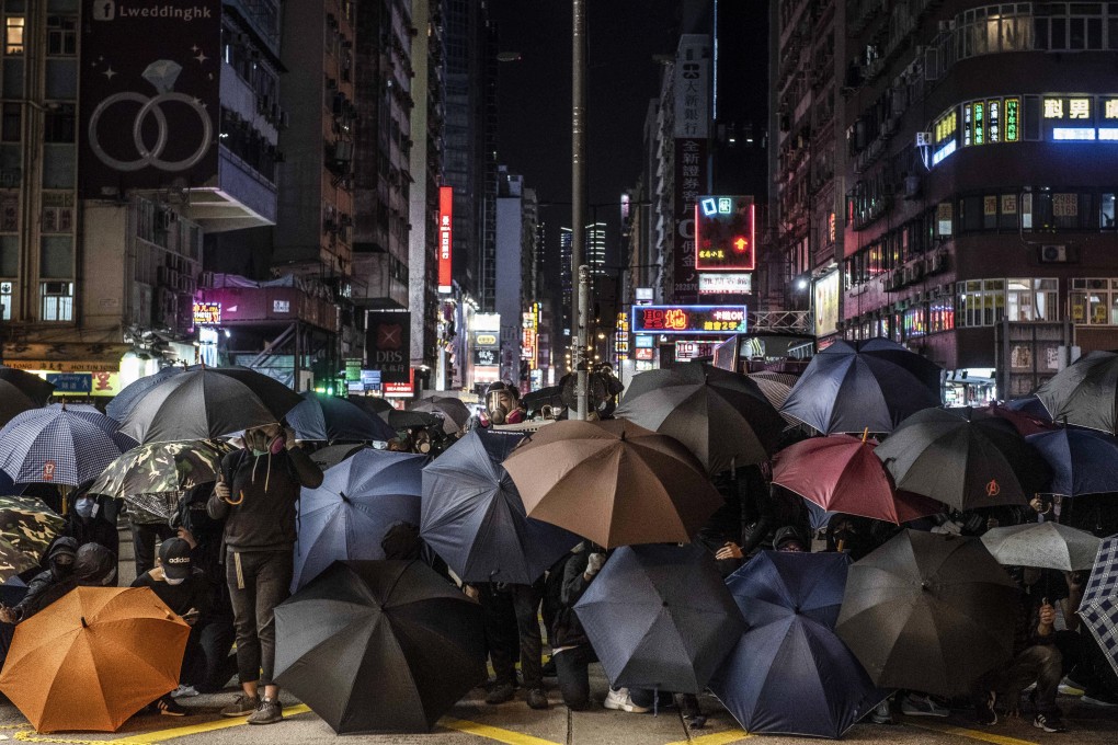 Protesters take cover under umbrellas during a protest outside Prince Edward MTR station on February 29. Photo: SOPA Images