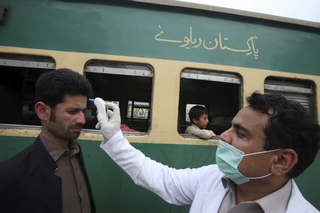 A worker checks the body temperature of a train passenger in Peshawar on March 17, 2020. Photo: AP