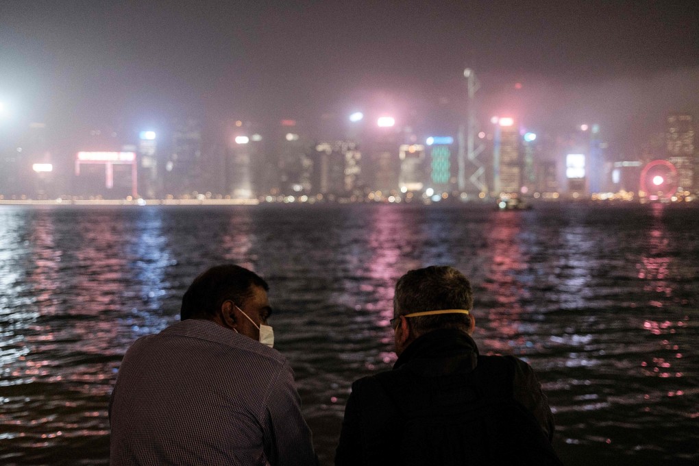 Two men in face masks chat while standing on a Kowloon promenade overlooking Victoria Harbour and the skyline of Hong Kong Island. Photo: AFP