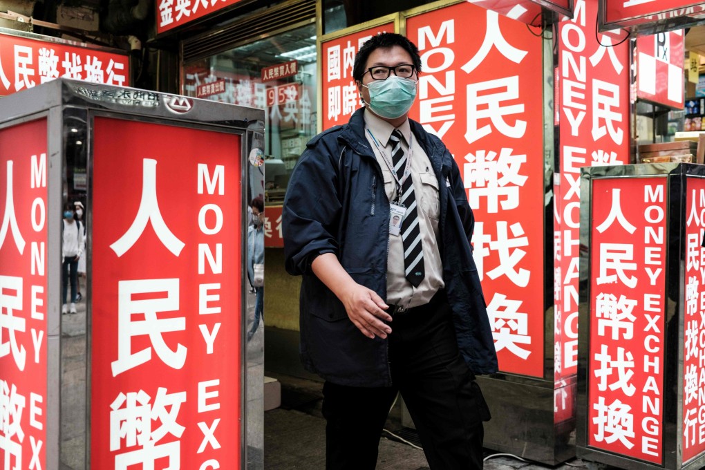A security worker, in a mask like most others in the city, walks past a money exchange outlet in Hong Kong on March 13. Photo: AFP