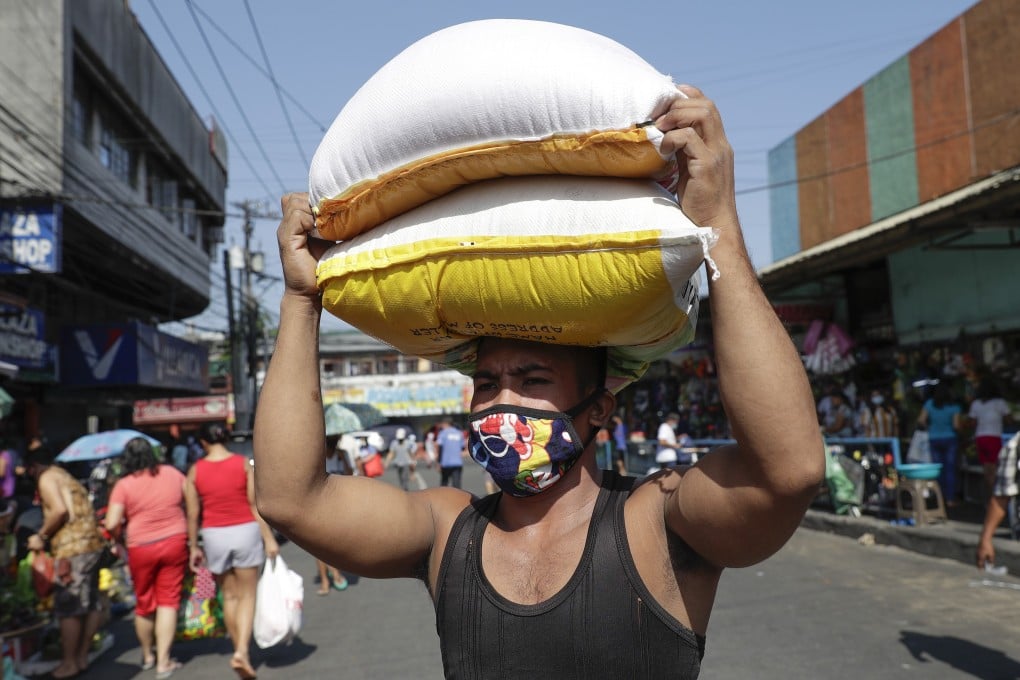 A worker carries sacks of rice before the Munoz market closes, after it cut its operations to four hours a day to curb the spread of the coronavirus in Metro Manila. Photo: AP