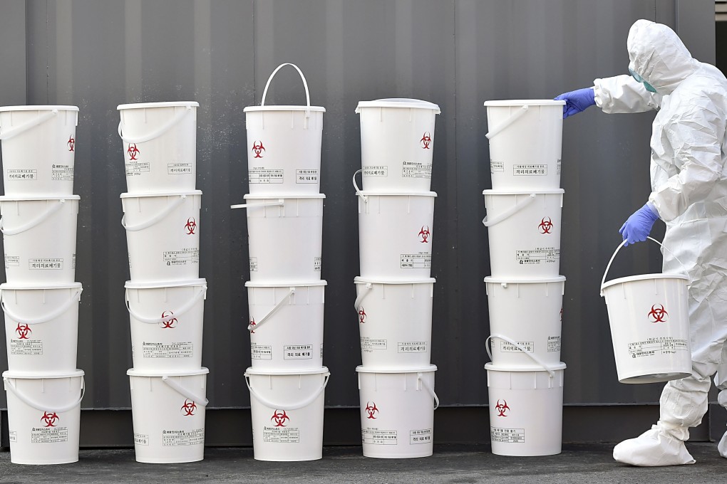 A medical staff member stacks plastic buckets containing medical waste from new coronavirus patients at Dongsan Hospital in Daegu, South Korea. Photo: AP
