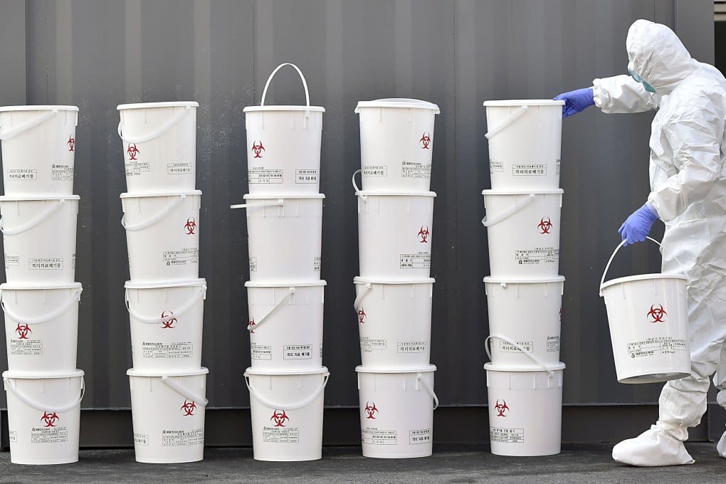A medical staff member stacks plastic buckets containing medical waste from new coronavirus patients at Dongsan Hospital in Daegu, South Korea. Photo: AP