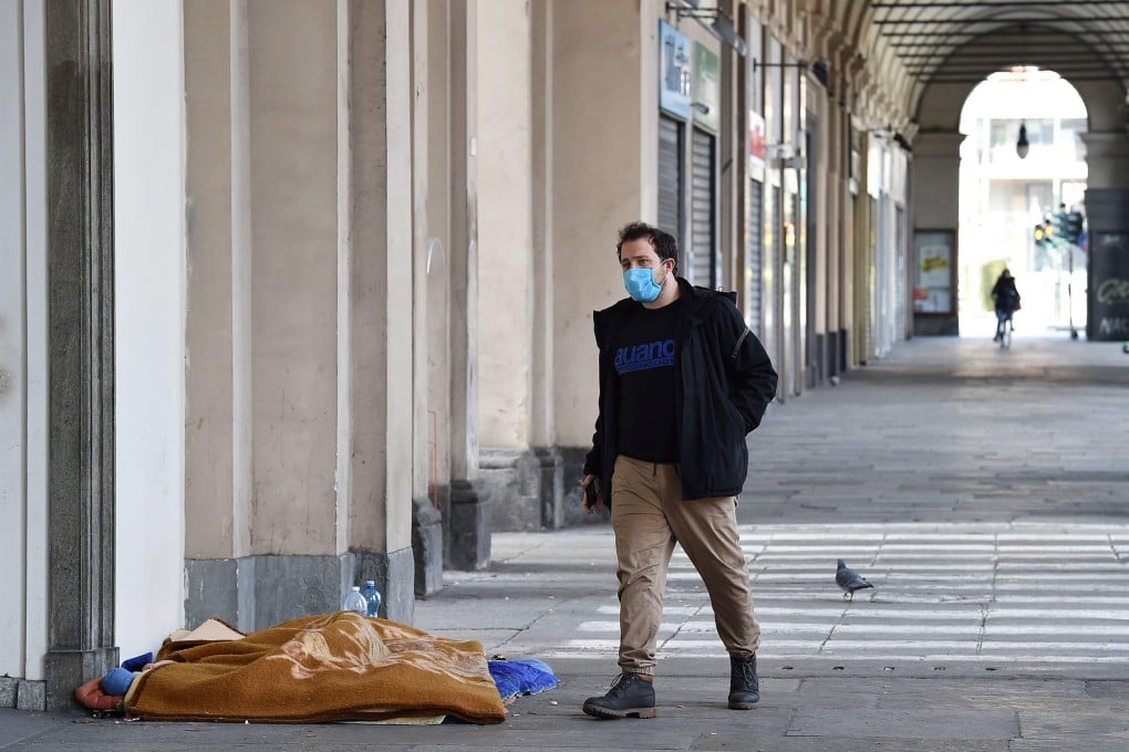 A man wearing a mask walks past a street sleeper in Turin, Italy, on March 17. Photo: EPA-EFE