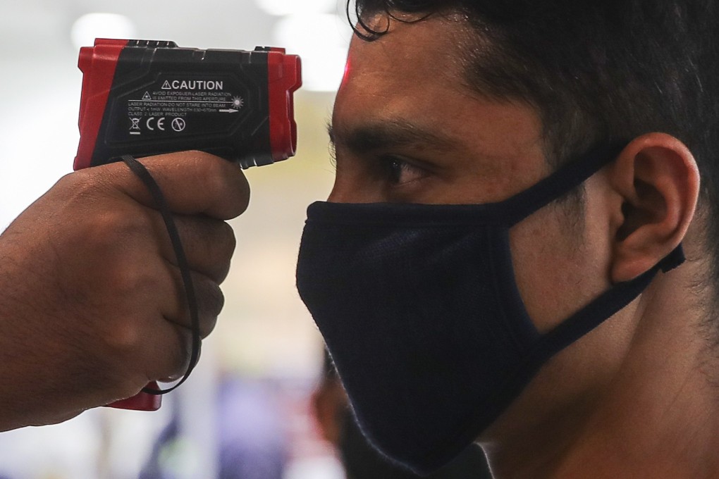 A security officer checks the tempature of a visitor inside a closed shopping centre in Malaysia on Wednesday. Photo: EPA