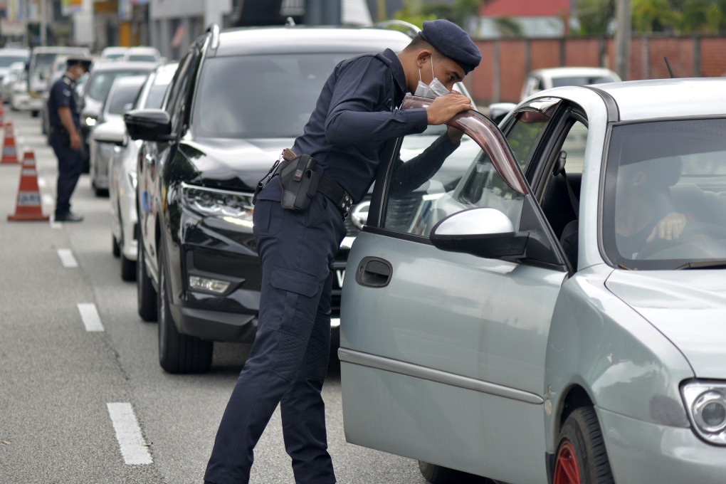 Police officers check vehicles at a roadblock to ensure that people adhere to a movement control order to block the spread of the new coronavirus in Malaysia. The army will be deployed to help the police. Photo: AP