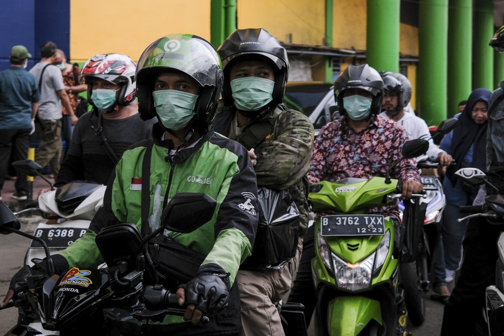 People wear protective face masks as they ride on their motorbikes outside a market in Jakarta, Indonesia. Photo: EPA