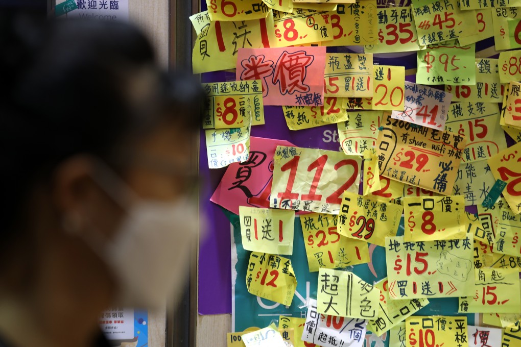 A woman wearing a mask walks past the shutters of a shop plastered with ads for discounted products in Tsim Sha Tsui on March 18. Small businesses in Hong Kong are struggling to survive as people stay home during the coronavirus outbreak. Photo: Nora Tam