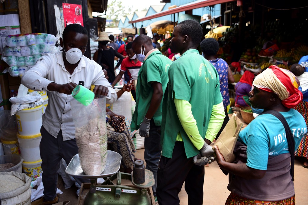 A trader wearing a protective mask weighs grains at the Kimironko market in Kigali, Rwanda on Tuesday. Photo: Reuters