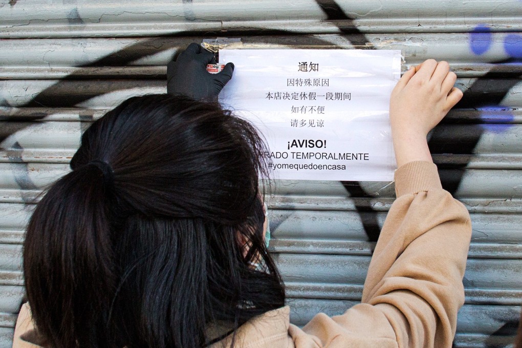 A Chinese woman puts up a closed notice at her business in Spain, along with an exhortation to citizens not to leave their homes during the coronavirus outbreak. Photo: Antolin Avezuela