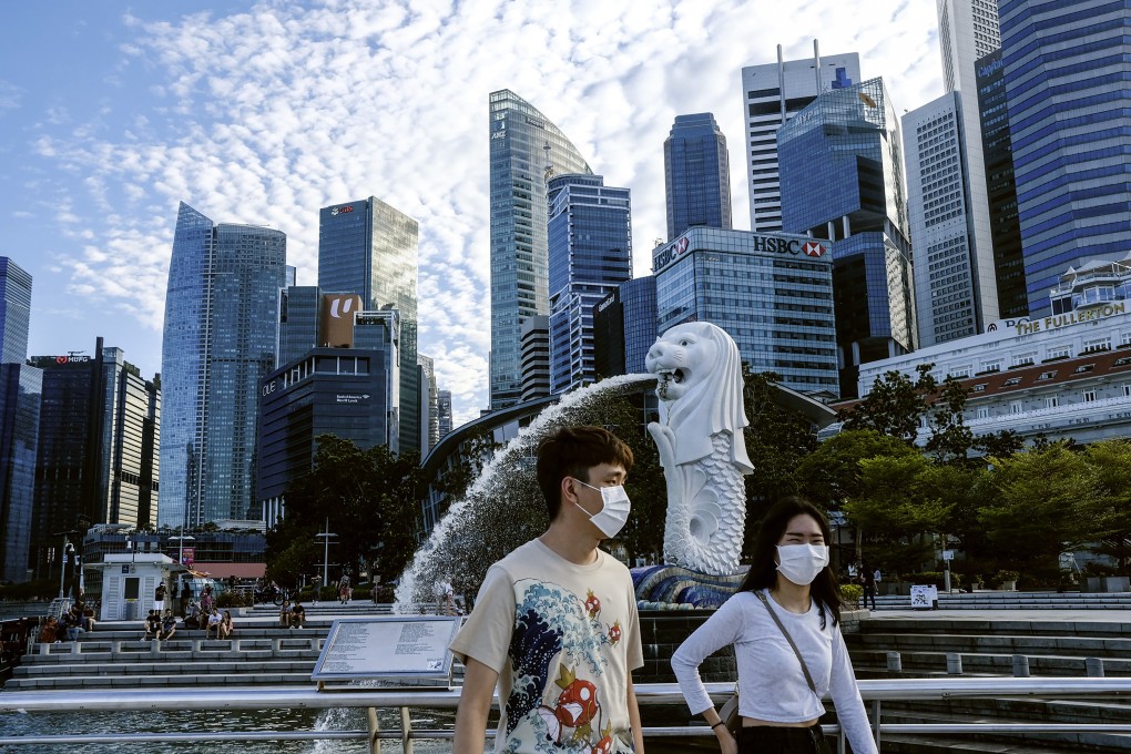 A couple wearing face masks walks past the Merlion statue in Singapore. Photo: AP