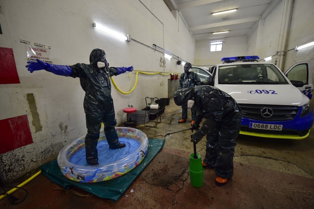 A volunteer in Pamplona, northern Spain, is sprayed with disinfectant after disinfecting a police car to prevent the spread of the virus. Photo: AP