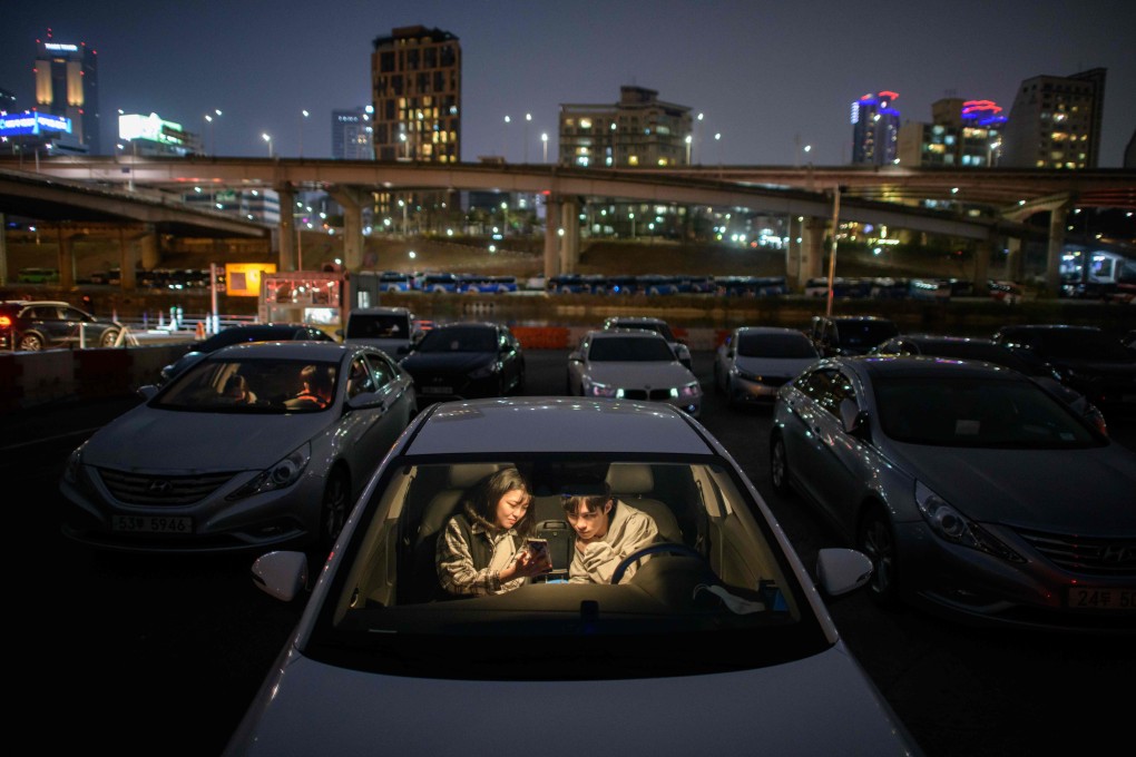 A couple check their mobile phones at a drive-through cinema in Seoul on March 21. The response of countries like South Korea and China are being examined, as public health experts look for models to emulate for authorities desperate to halt the spread of the novel coronavirus. Photo: AFP