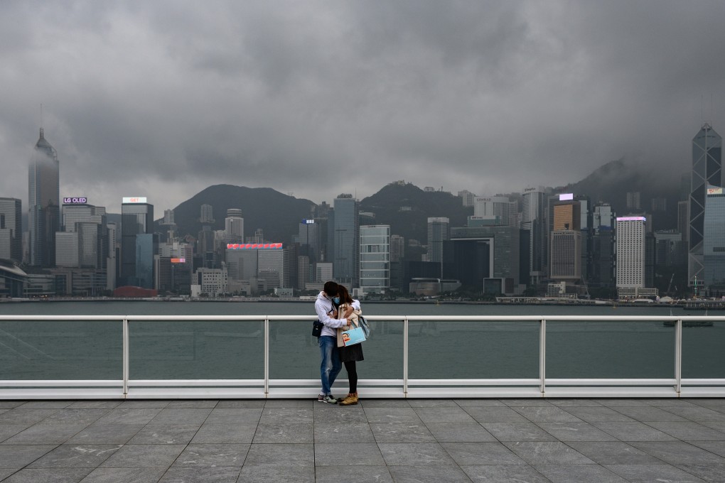 A couple wearing face masks embrace in front of the city’s skyline in Tsim Sha Tsui on February 14. Photo: AFP