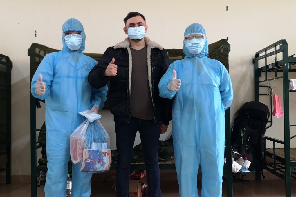 British tourist Gavin Wheeldon raises a thumbs-up with two medical staff in his room at Son Tay Military School quarantine camp in Hanoi. Photo: Gavin Wheeldon