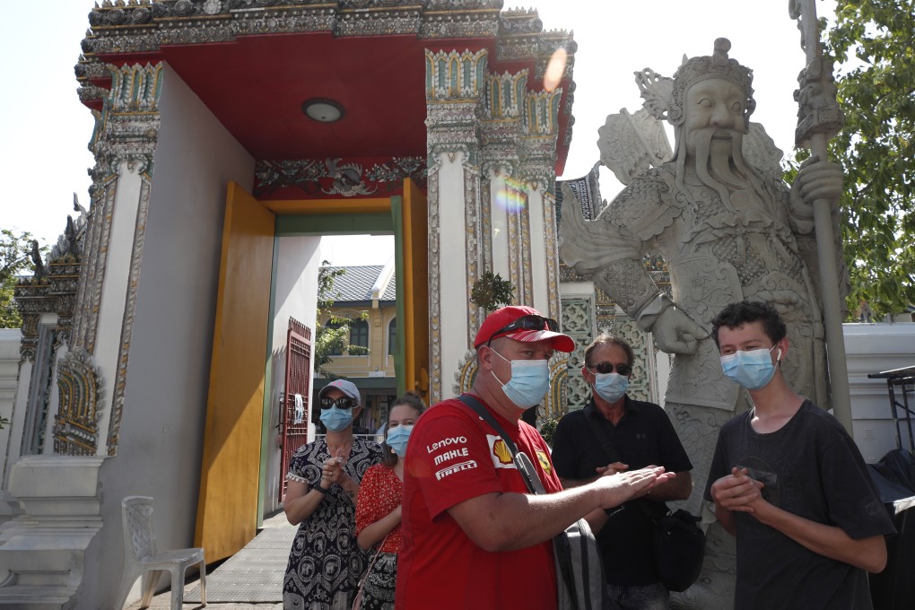 Tourists wearing face masks sanitise their hands at Wat Pho, in Bangkok, Thailand, on March 13. Photo: EPA