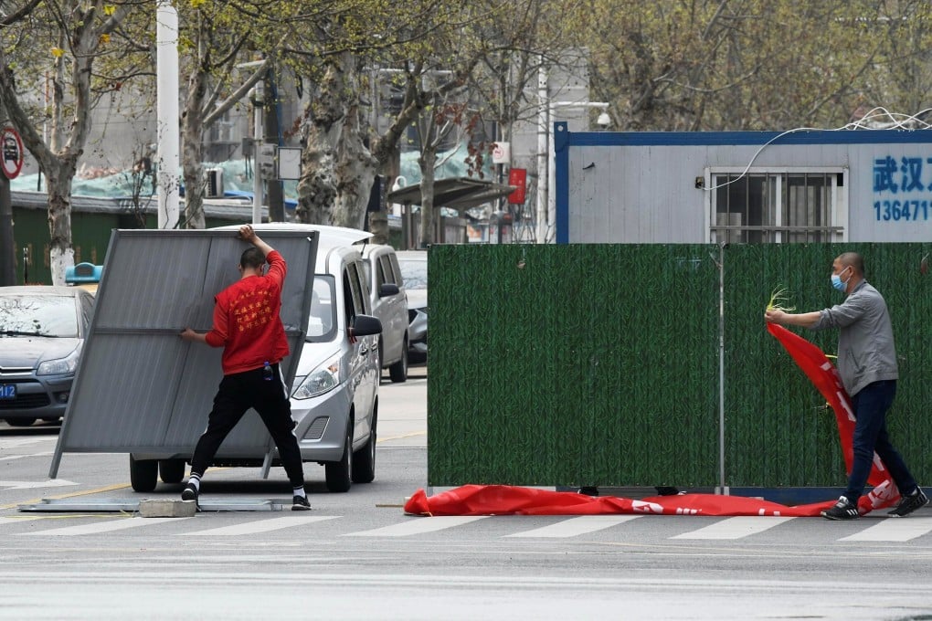 Workers remove barriers from a street in Wuhan as lockdown measures are eased. Photo: Reuters