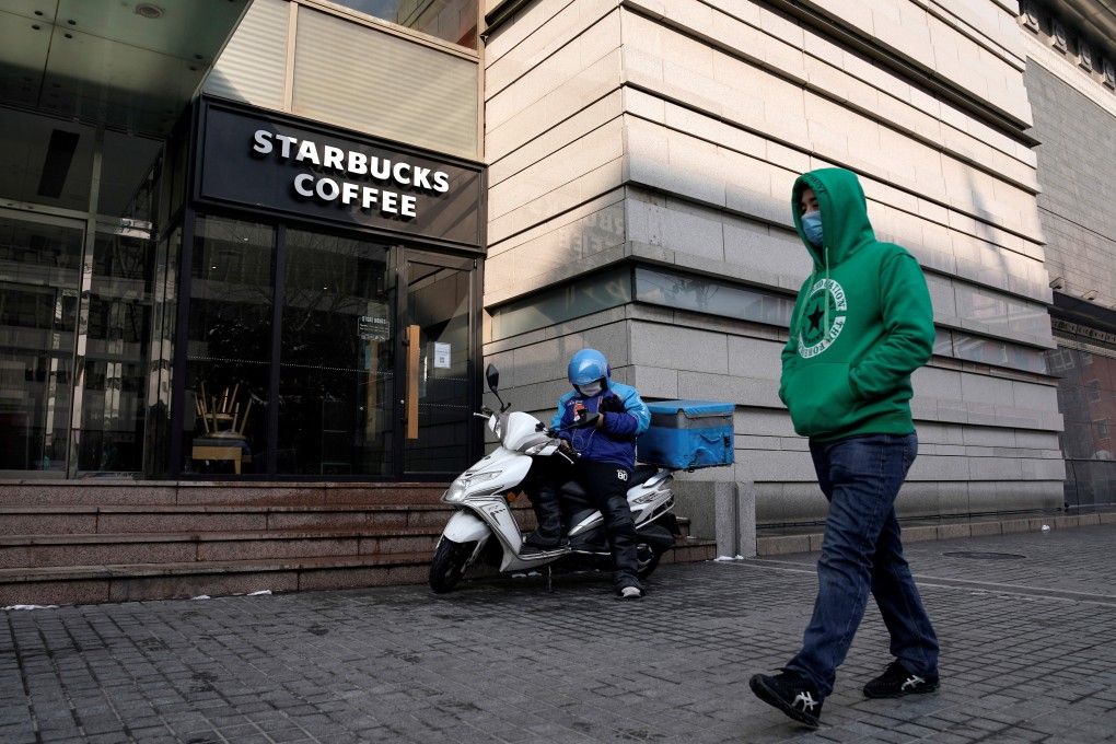 A man wearing a face mask walks past a deliveryman as he waits outside a Starbucks store in Beijing. Photo: Reuters