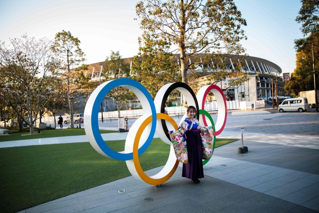 A woman wearing a traditional Japanese kimono poses next to the Olympic rings in front of the Japan National Stadium. Photo: AFP