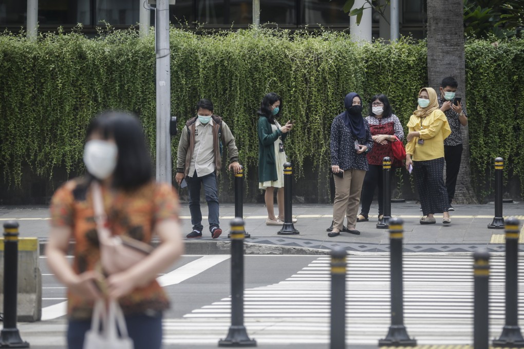 Indonesians wear protective face masks as they wait to cross the street in Jakarta. Authorities have urged people to avoid public gatherings, but many are still going to work, fearful that they might lose their jobs. Photo: EPA-EFE